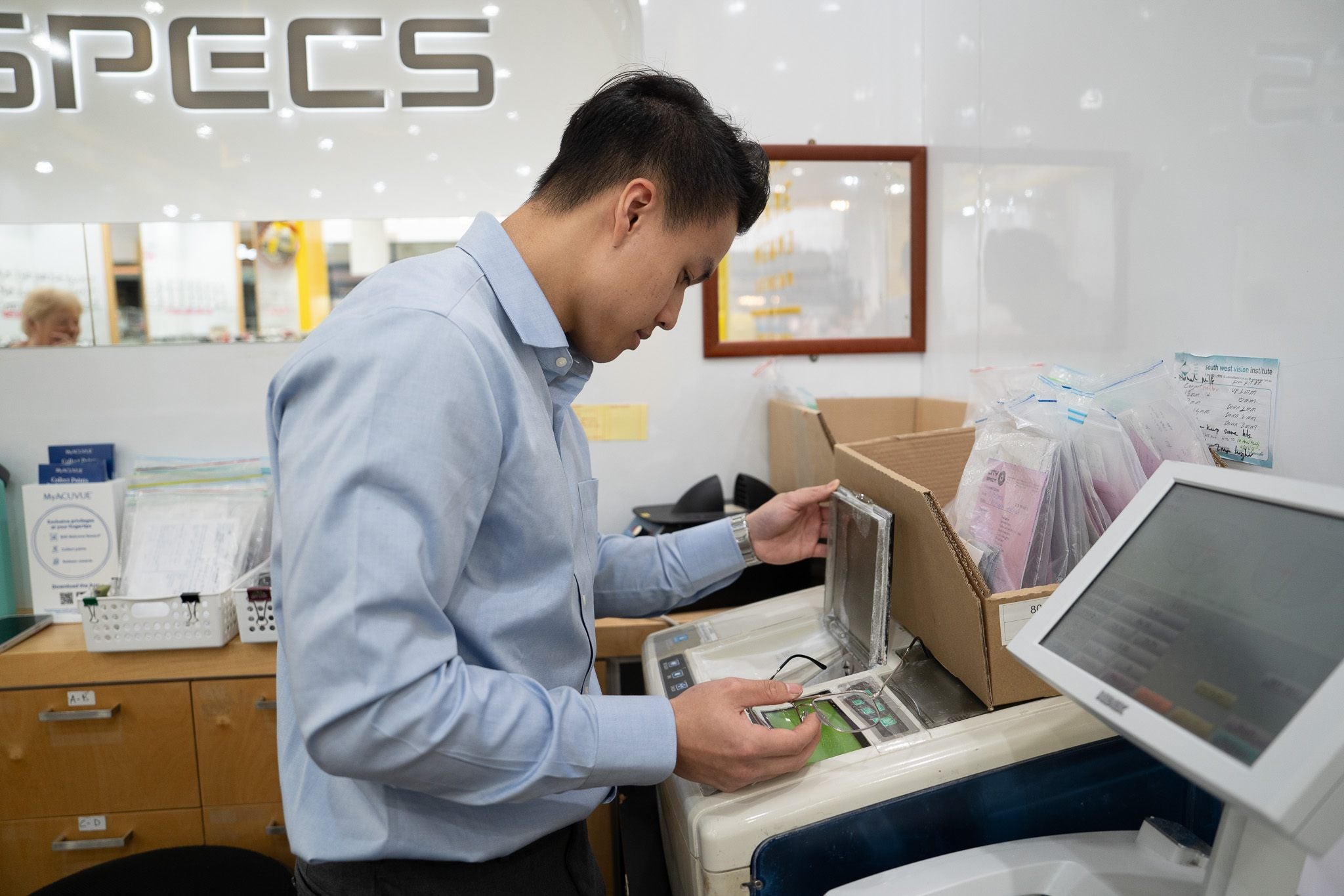 City Optics team member preparing glasses with in-store optical lab equipment